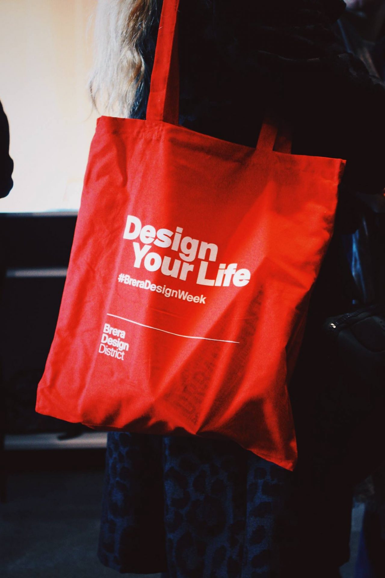 red tote bag with white text stating design your life